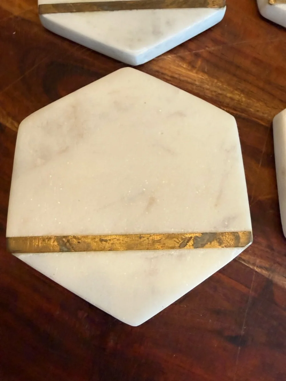 Hexagonal white marble coasters featuring a brass inlay design